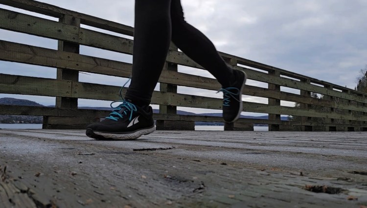 Pieds avec espadrilles en train du courir sur un pont de bois