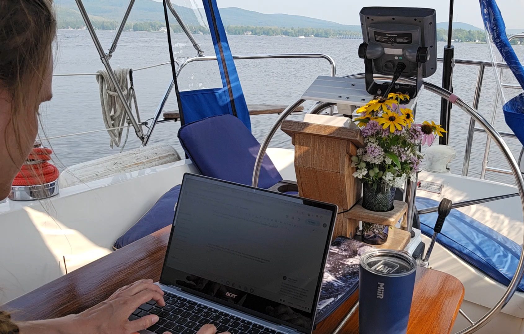 Joe assise à son clavier dans le cockpit du voilier
