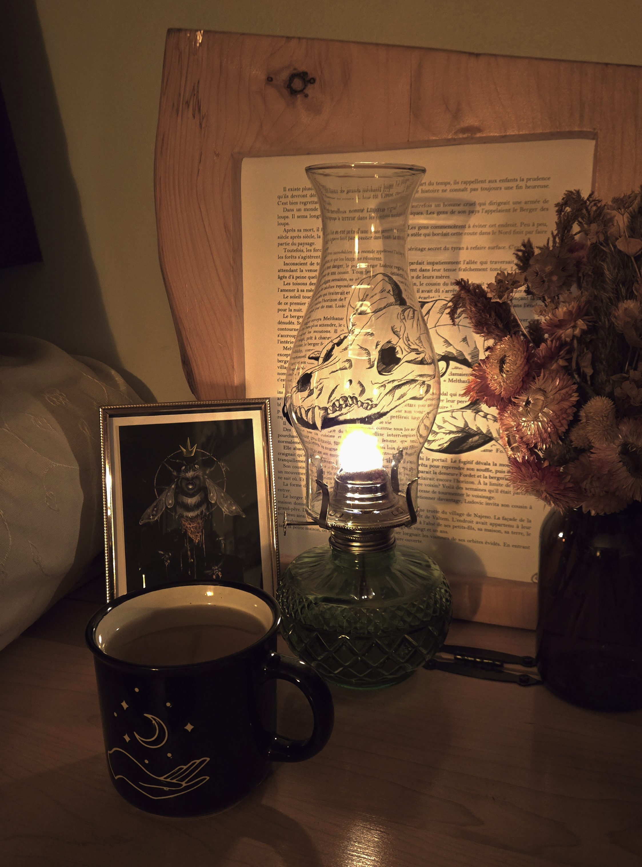 Tasse de tisane, une lampe à l'huile allumée et quelques décorations, cadres et bouquet de fleurs séchées