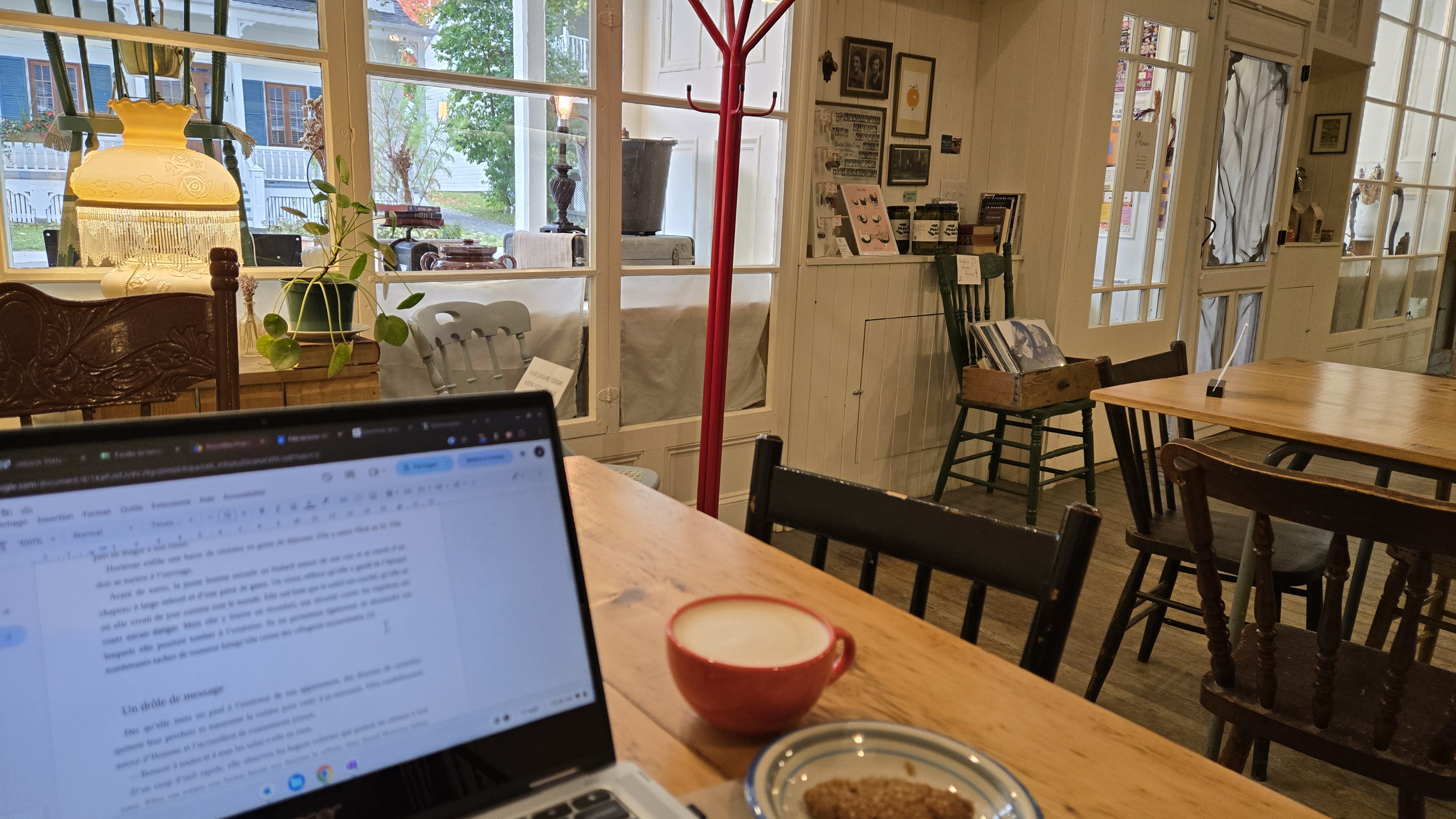 Vue sur un écran d'ordinateur portable avec en arrière-plan, le décor d'un café dans un ancien magasin général avec ses meubles antiques